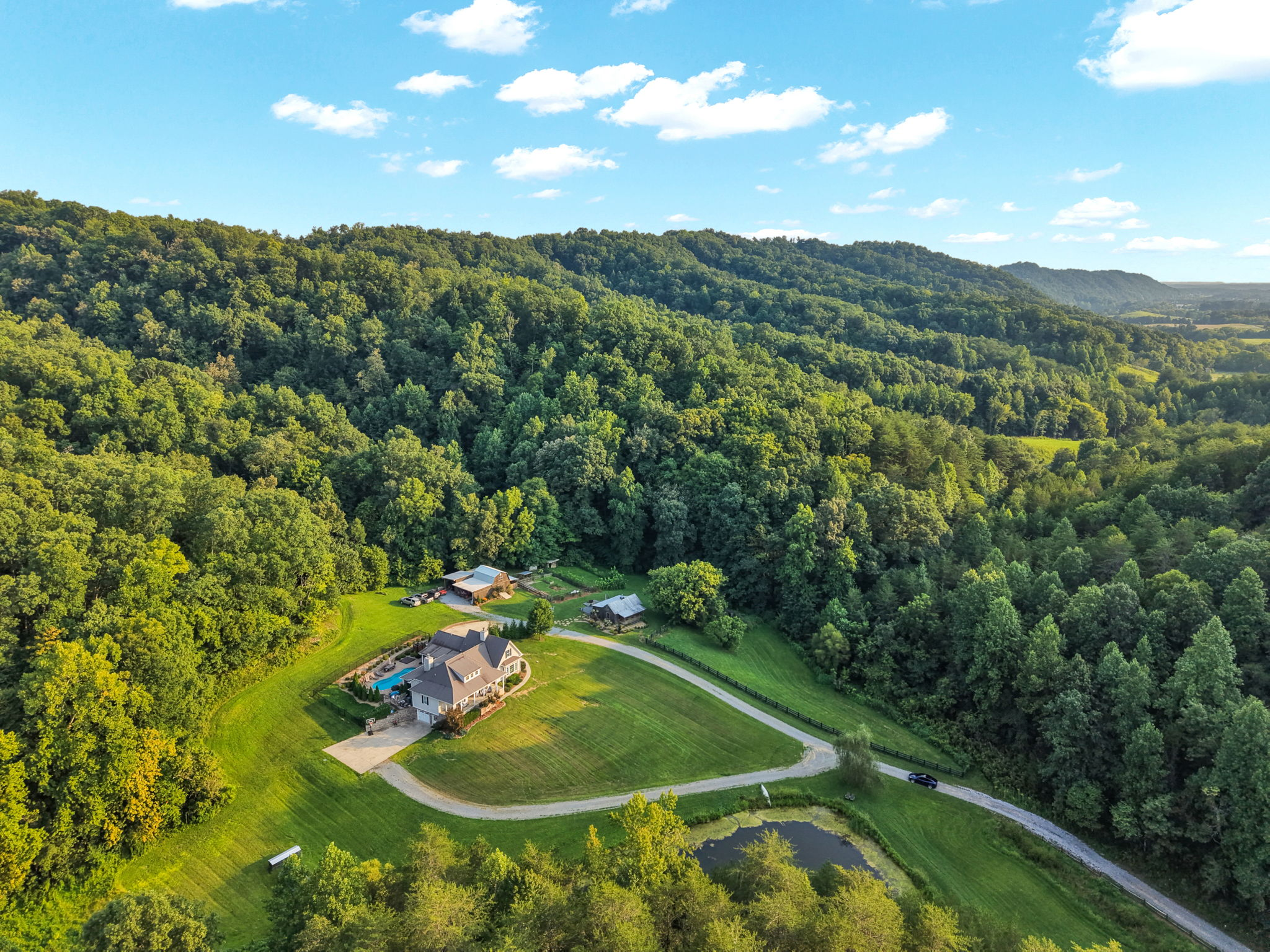Aerial view of the residence, pond, private drive and wooded East Tennessee landscape