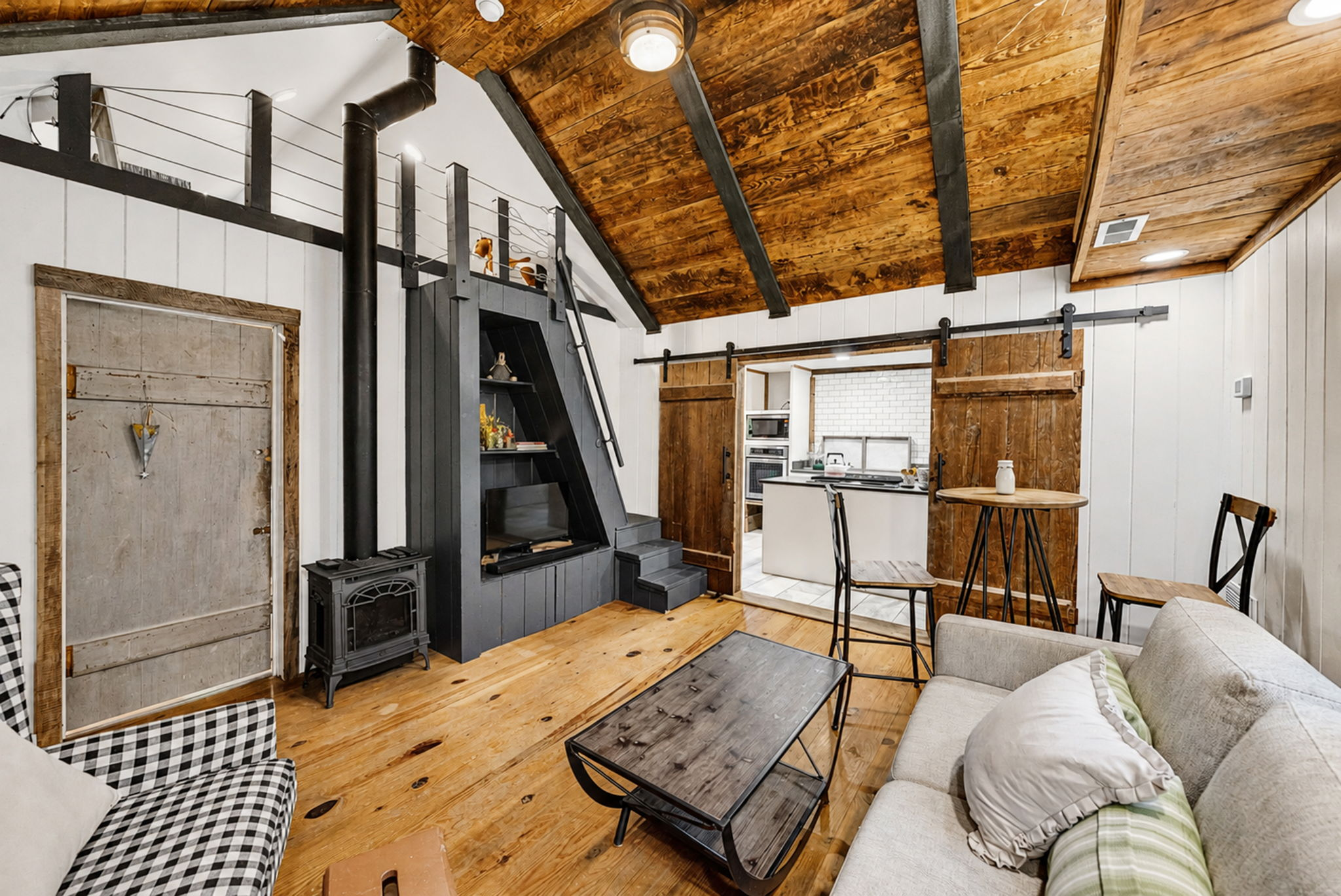 Guest cabin living room with vaulted wood ceiling, stove and loft