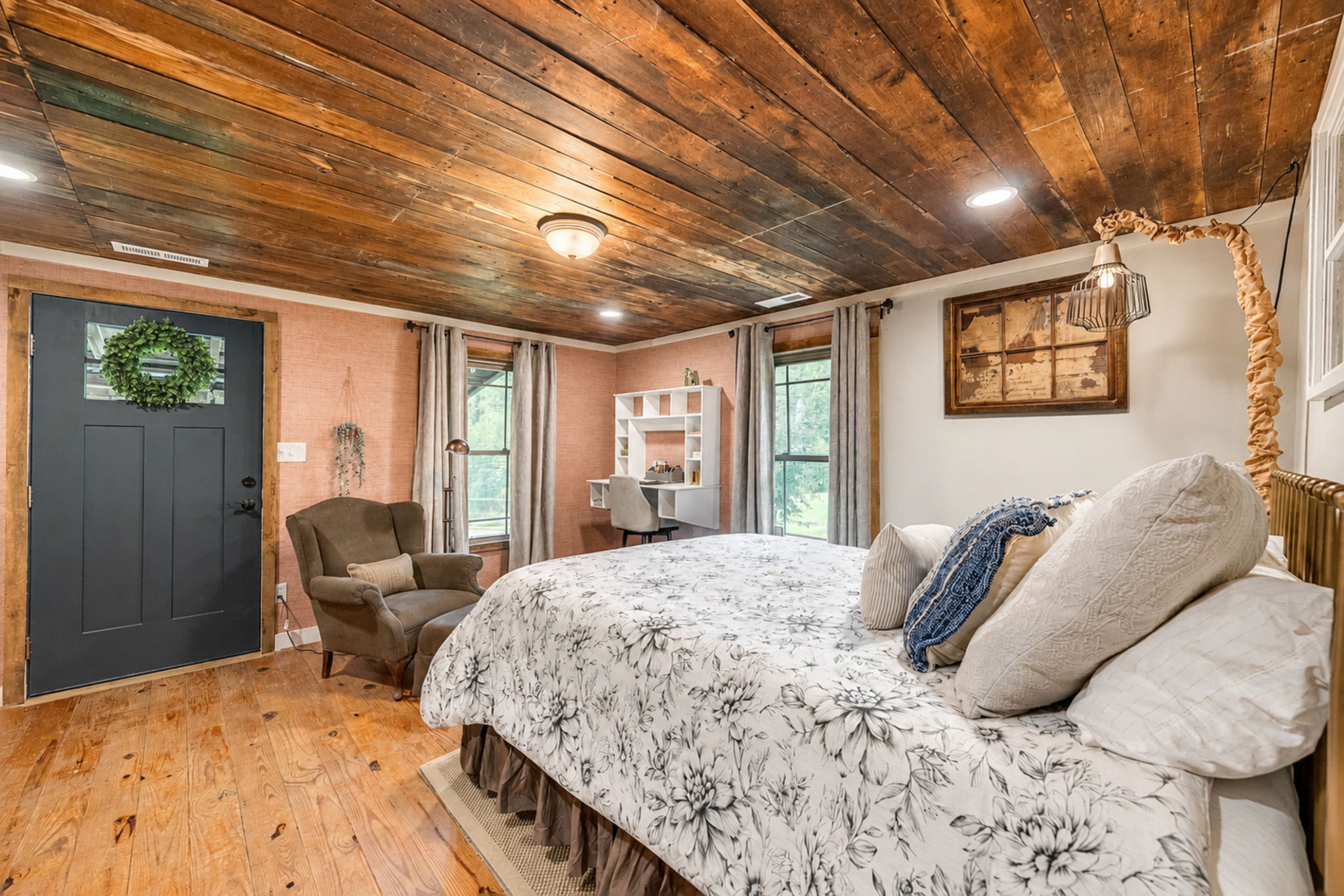 Guest cabin bedroom with wide-plank floors and warm wood ceiling