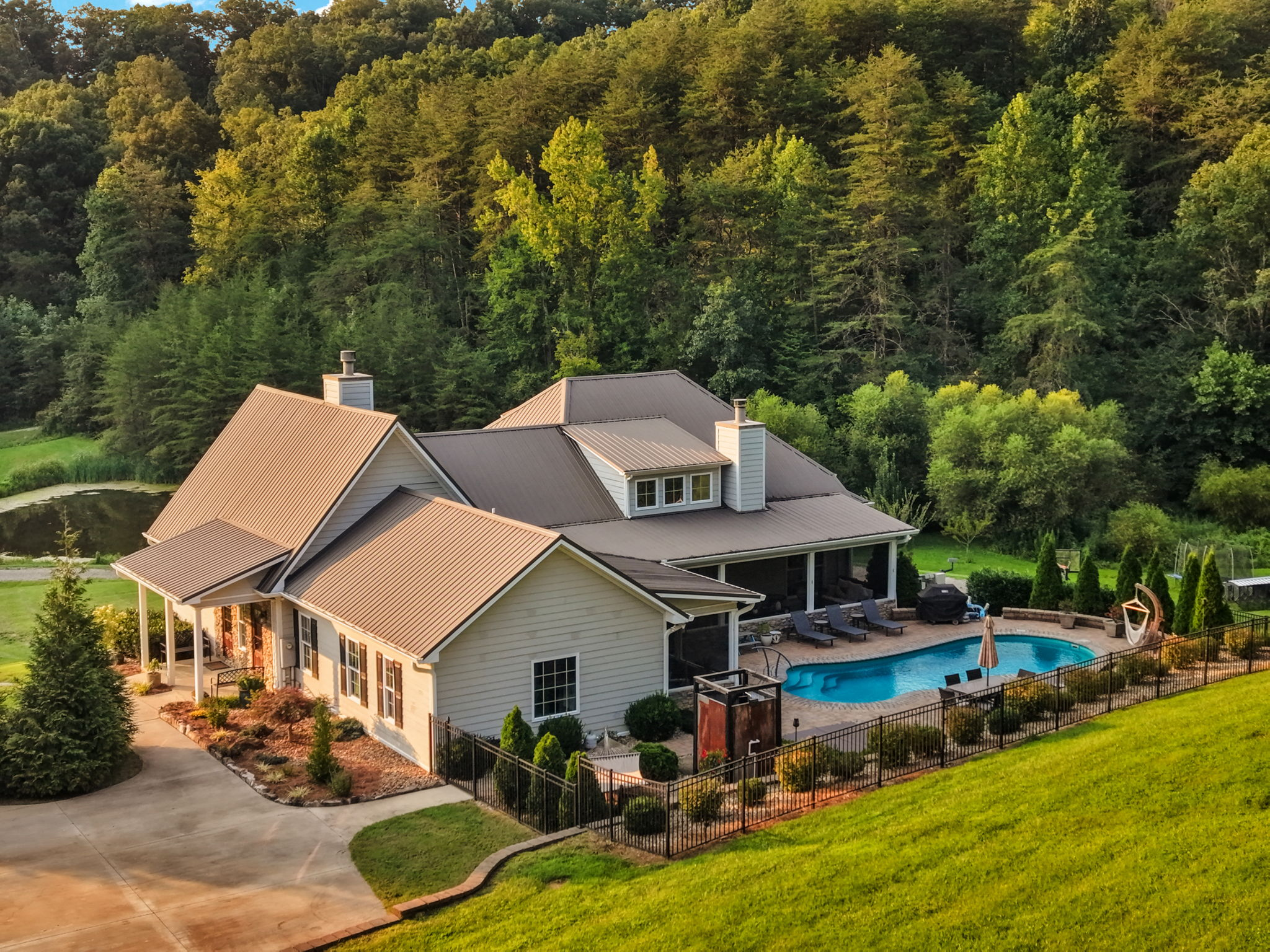 Elevated view of the residence, pool terrace, pond and surrounding woodland